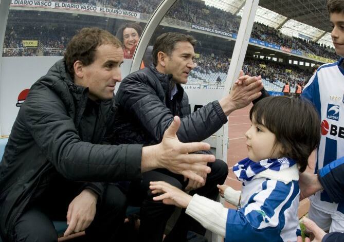 Arrasate y Montanier saludan a varios niños en el banquillo de Anoeta antes de un partido.