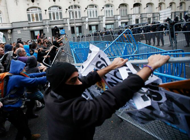 Varios manifestantes intentan echar abajo las vallas de seguridad instaladas por la policia