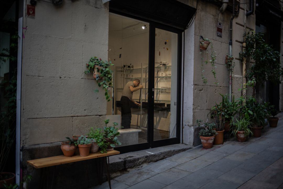 Un hombre se prepara para abrir su tienda durante el desconfinamiento 