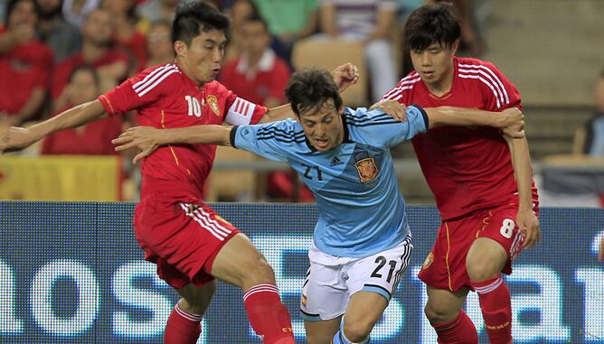 El centrocampista de la selección española, David Silva, intenta superar la defensa de los jugadores de China, Zheng Zhi y Hao Junmin, durante el partido que disputan esta noche en el estadio Olímpico de Sevilla, último partido preparatorio para la Euroco