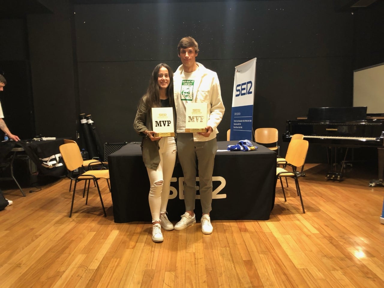 Nuria Rábano y Le Normand posan con sus premios en el escenario del salón de actos del Deutsche Schule San Sebastián