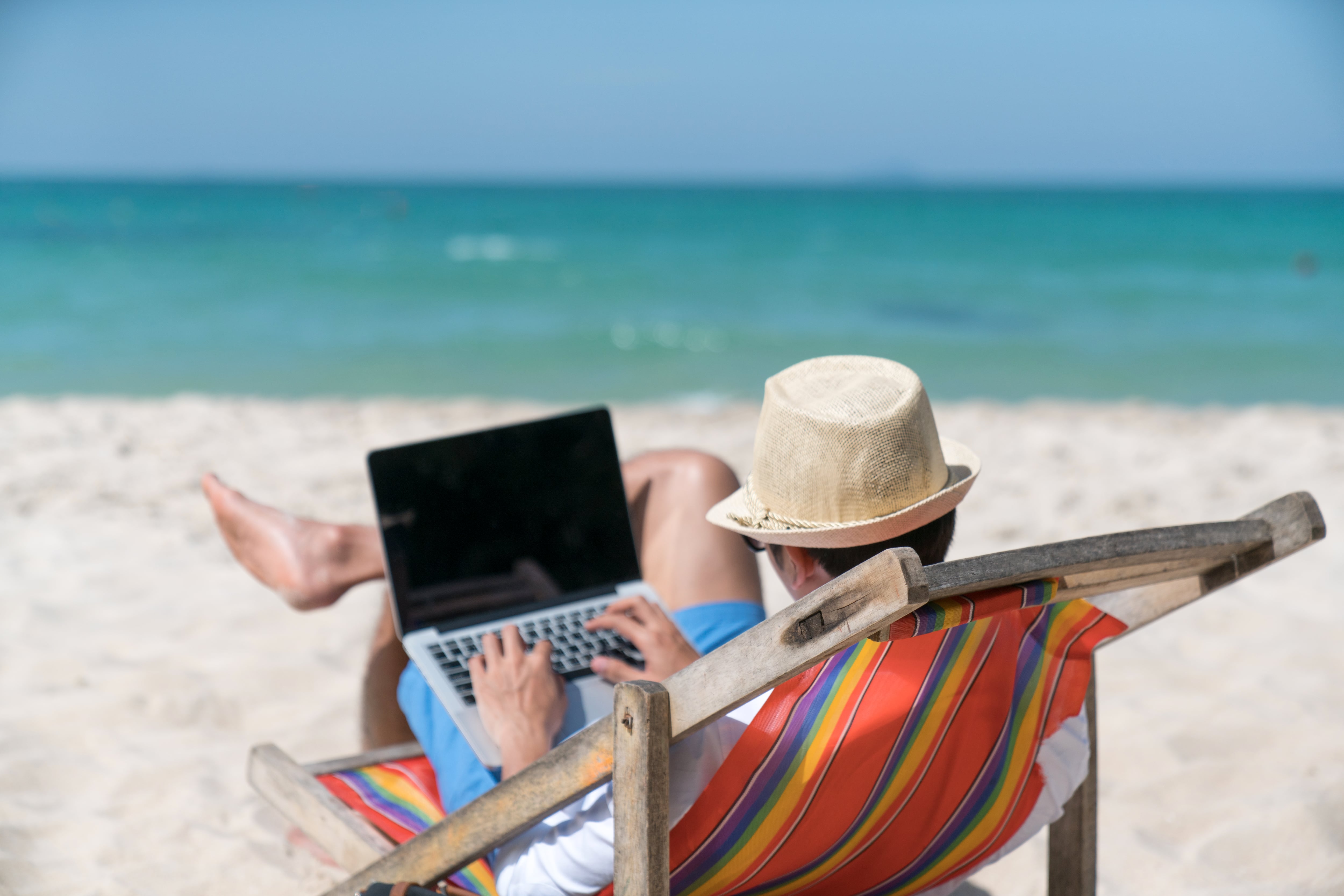 Un hombre en la playa con ordenador.