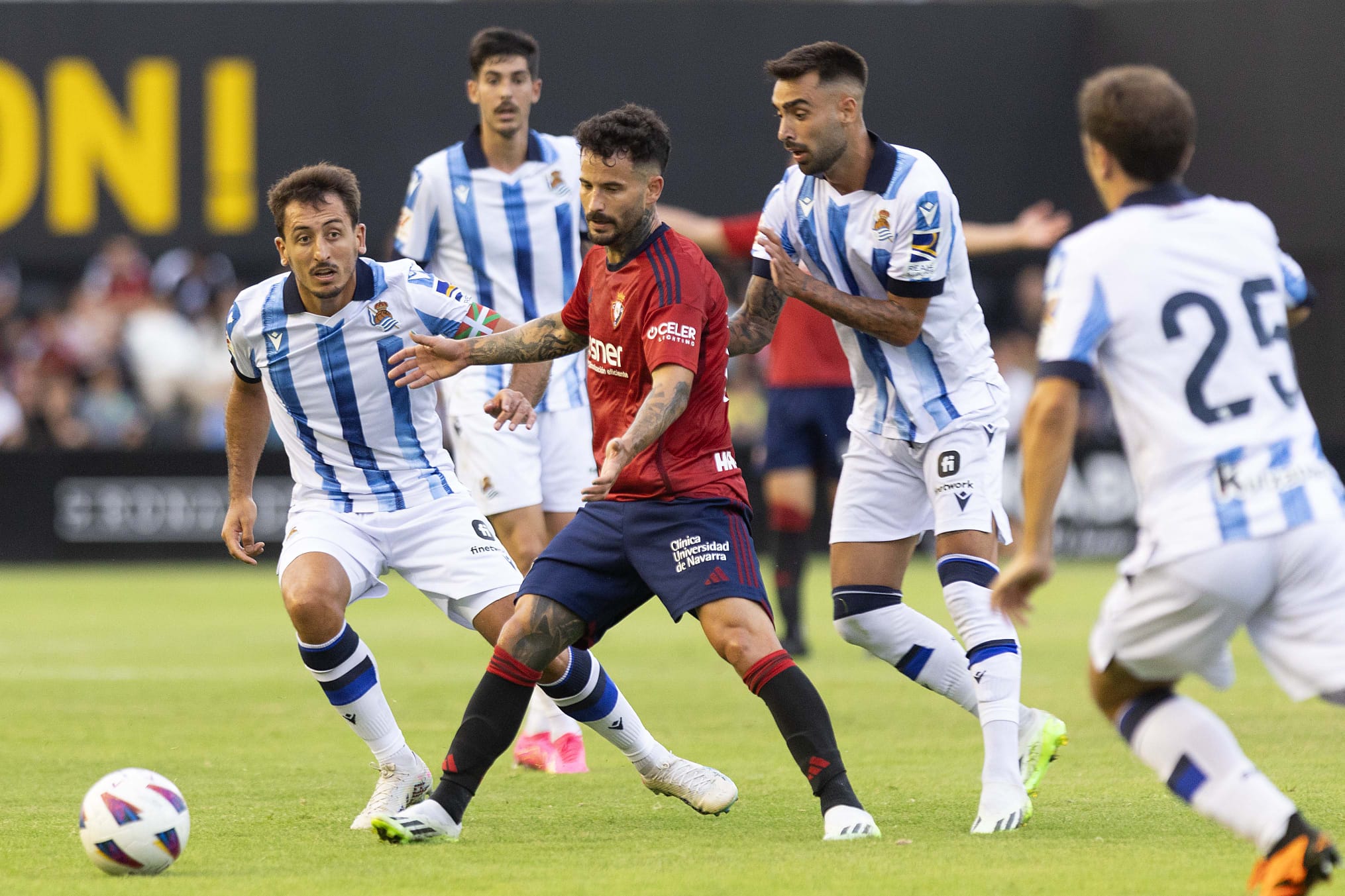 Rubén García vistiendo la camiseta Adidas de Osasuna rodeado de jugadores de la Real Sociedad vestidos por Macron