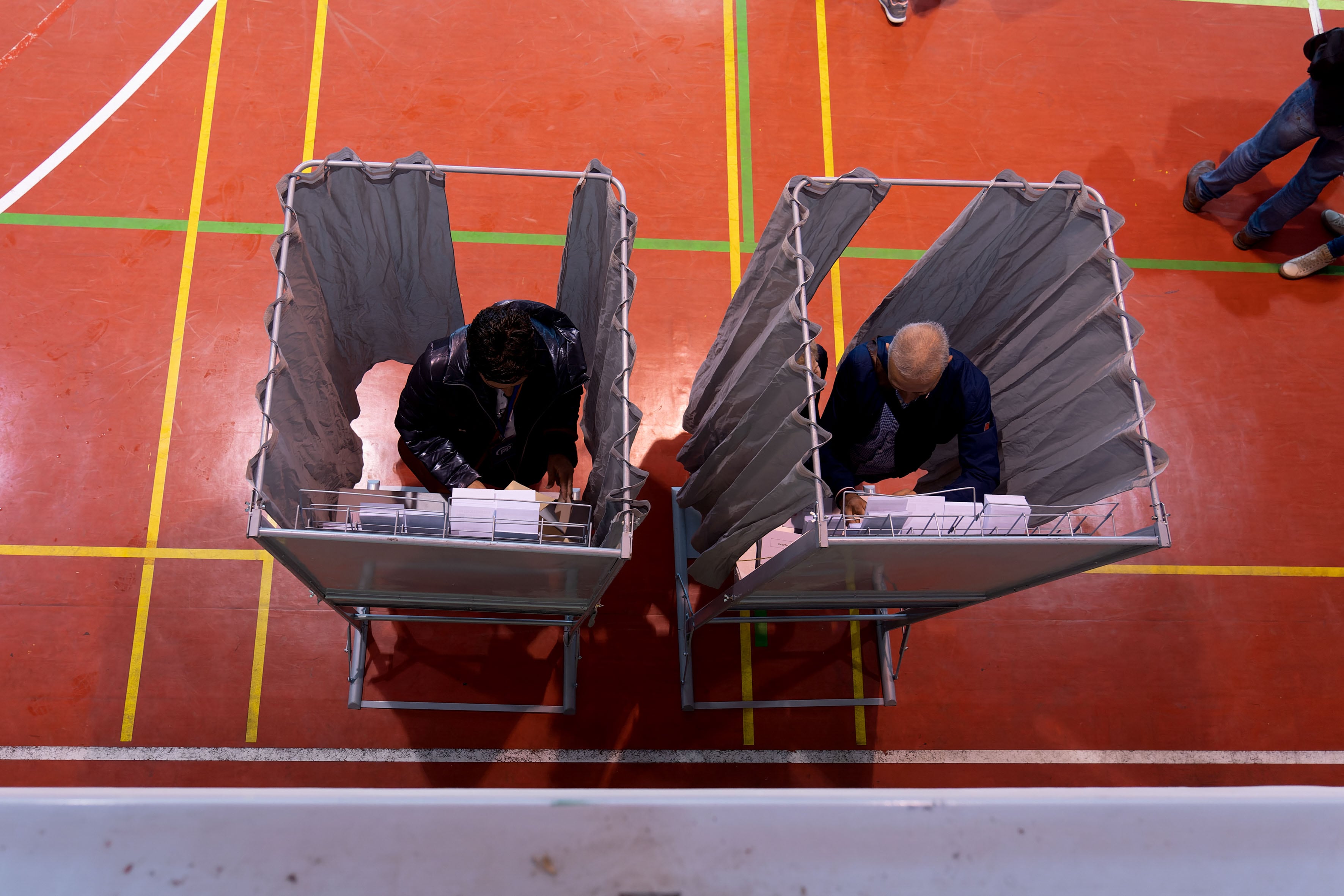 Votantes eligen sus papeletas mientras ejercen su derecho al voto este domingo en un colegio electoral.