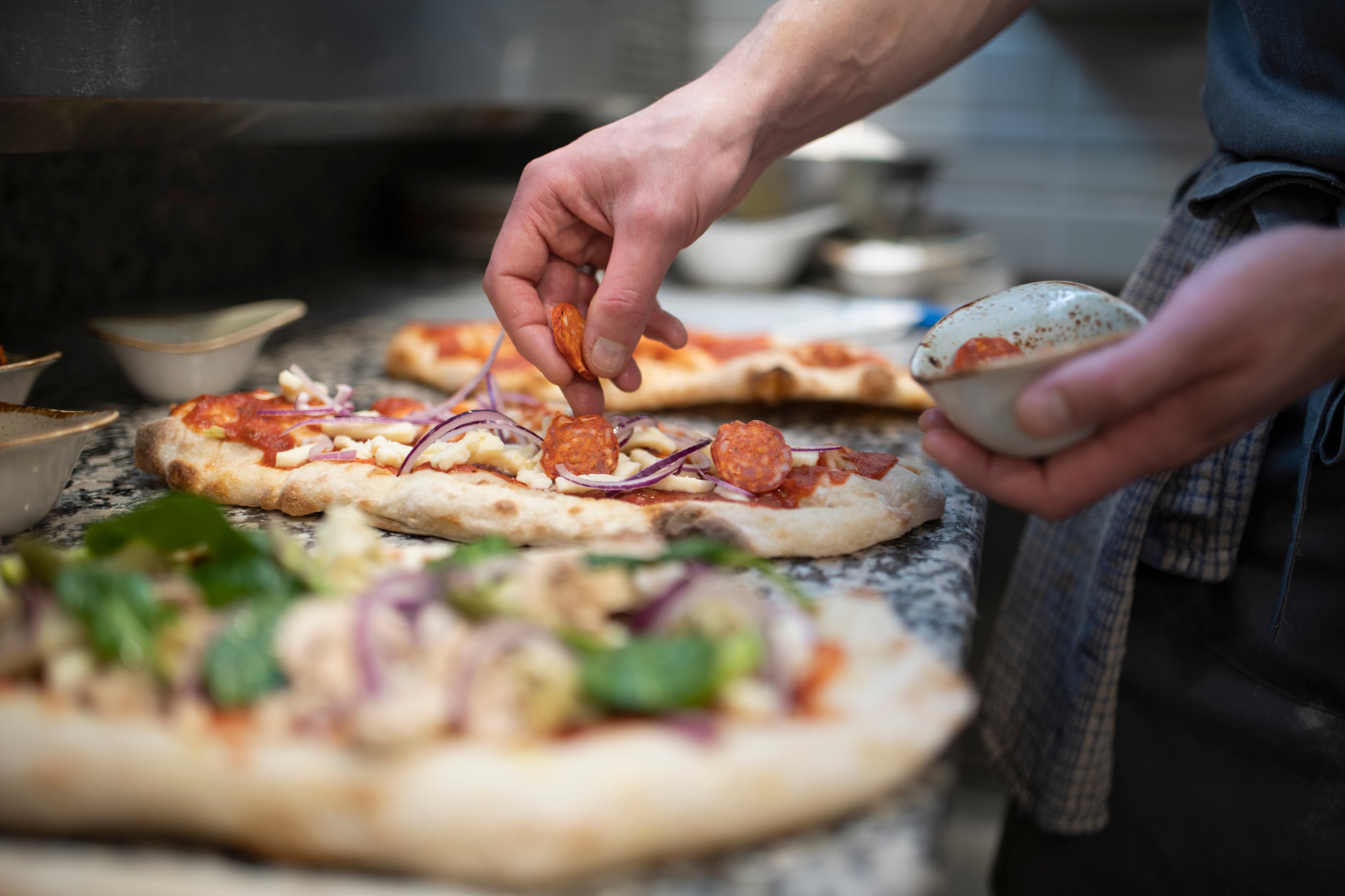 Un chef preparando tres pizzas artesanales