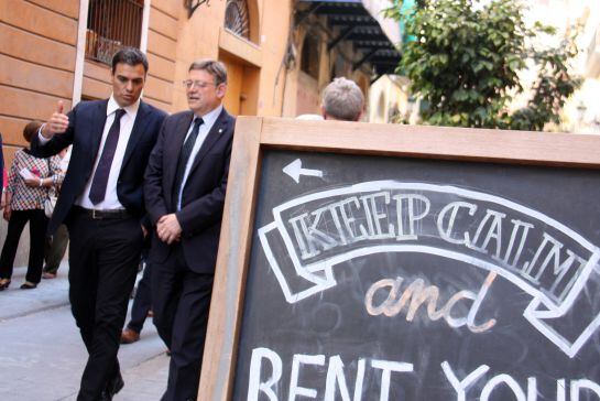 Pla tres quarts. El líder socialista Pedro Sánchez i el presidour bient valencià Ximo Puig passegen camí de la seu del PSPV i passen per davant d&#039;un cartell &#039;Keep calm and rent your bike&#039;. Horitzontal. 19/05/2016.