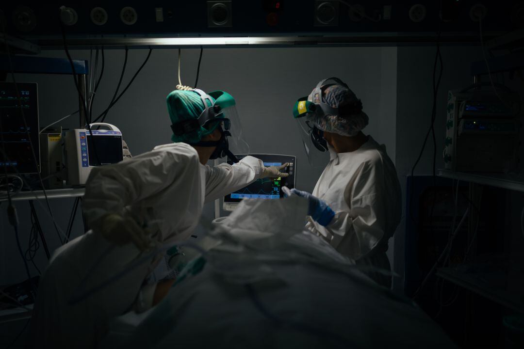 Personal sanitario atendiendo a un paciente de COVID-19 en la UCI.