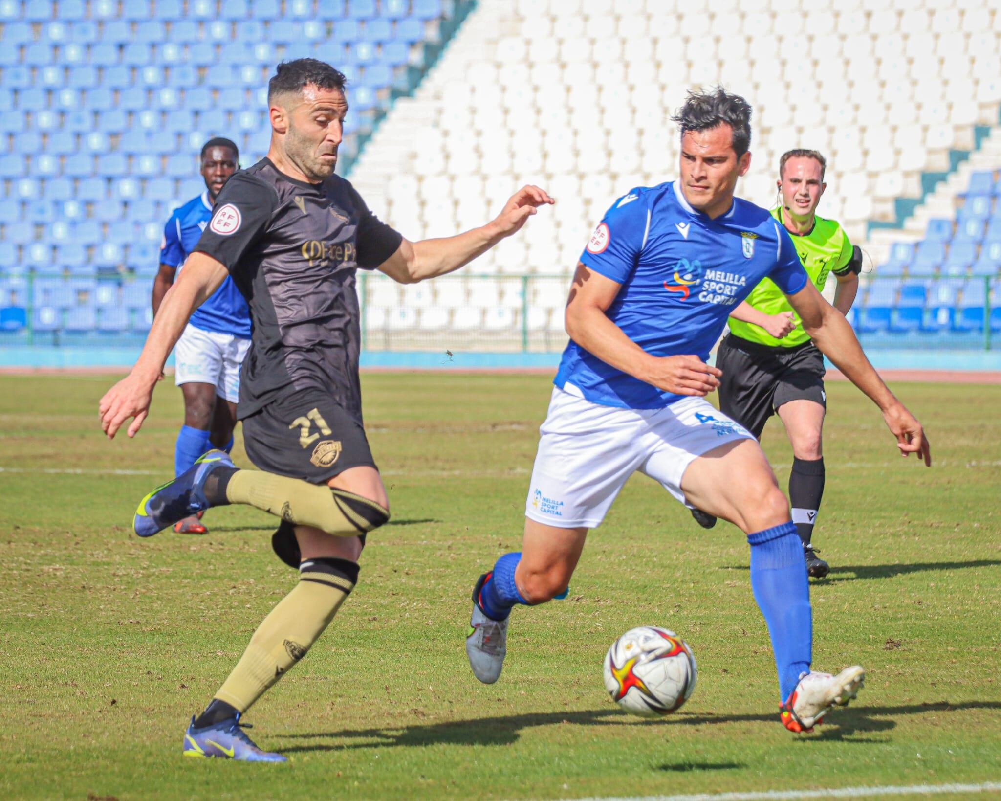 Benja disputa un balón ante un defensor del Melilla