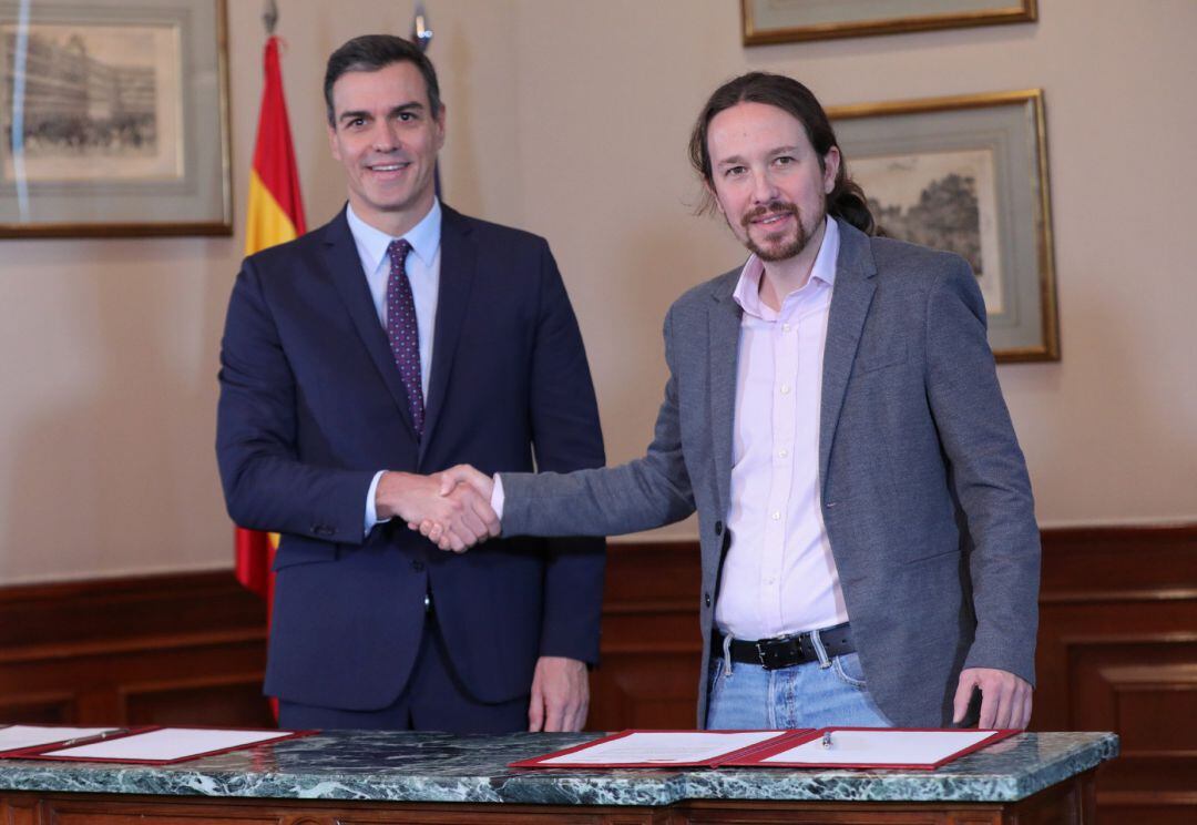 El presidente del Gobierno en funciones, Pedro Sánchez y el líder de Podemos, Pablo Iglesias, se estrechan la mano en el Congreso de los Diputados tras firmar el principio de acuerdo para compartir un gobierno de coalición.