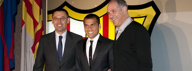 El jugador brasileño del FC Barcelona Dani Alves (c), posa para los medios tras renovar su contrato con la entidad azulgrana junto a Josep Maria Bartomeu (i), vicepresidente deportivo, y Andoni Zubizarreta, director deportivo