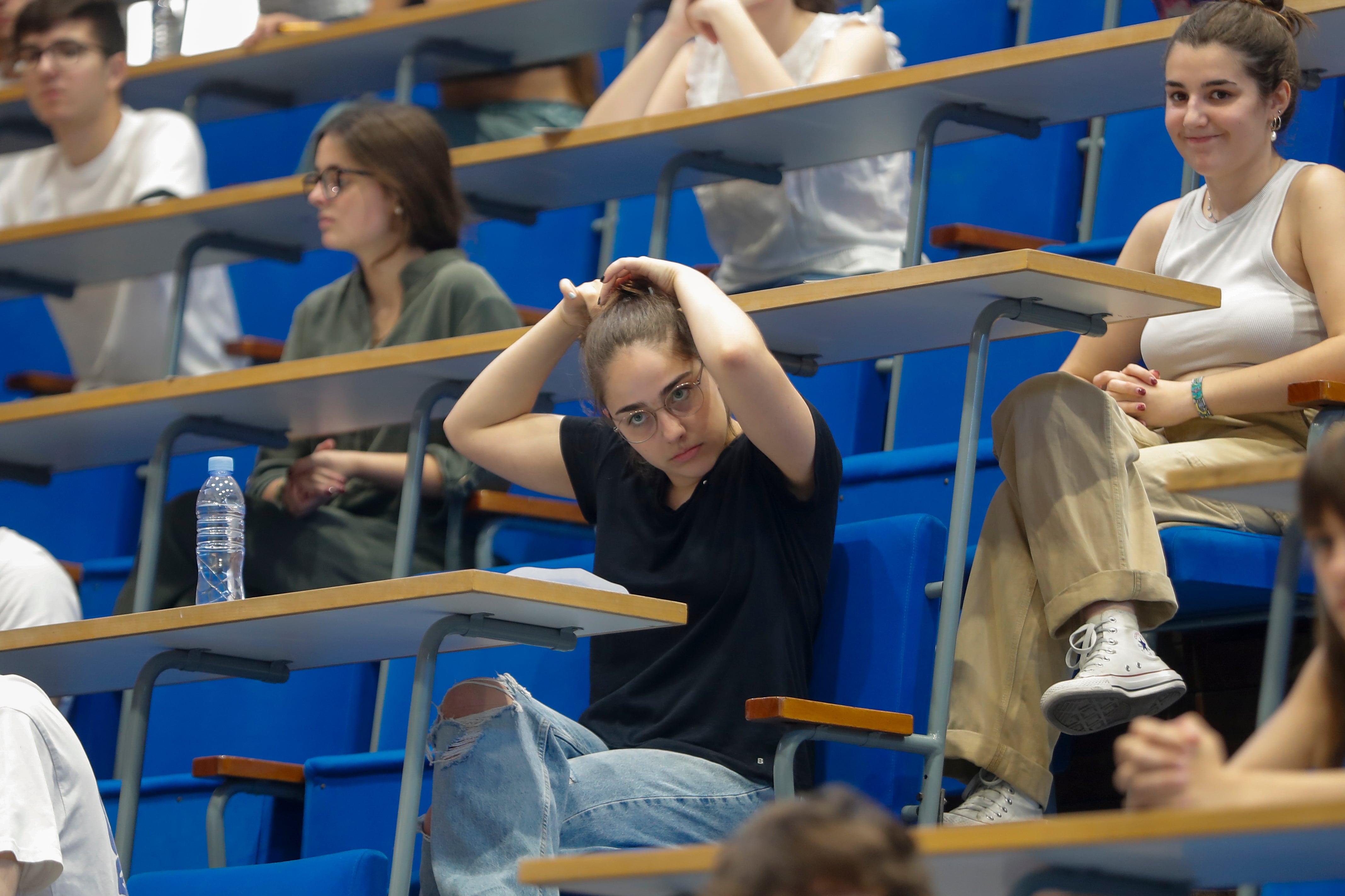 Una alumna se recoge el pelo para obedecer la normativa de la EBAU que obliga a que las orejas del alumno sean visibles antes de comenzar los exámenes de la Evaluación del Bachillerato para el Acceso a la Universidad (EBAU) en Zaragoza