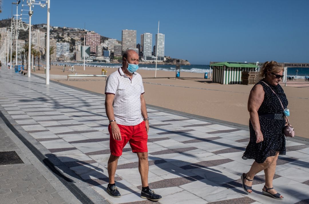 Dos personas caminando por el paseo marítimo de Benidorm. 