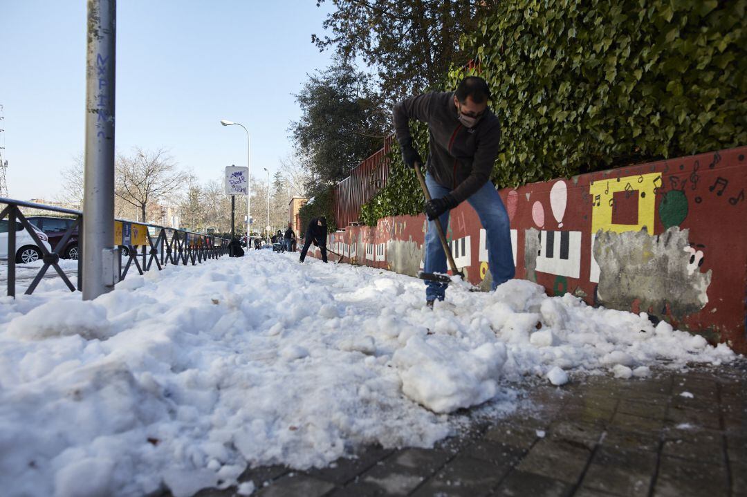 Varios familiares colaboran en la limpieza del hielo y la nieve en las inmediaciones del colegio Amadeo Vives tras la gran nevada por el paso de la borrasca &#039;Filomena&#039;, en Madrid