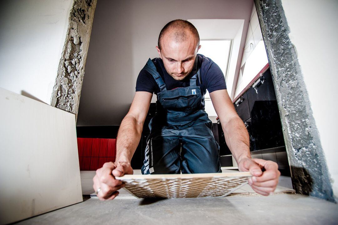 Un profesional de la construcción coloca un azulejo en una obra