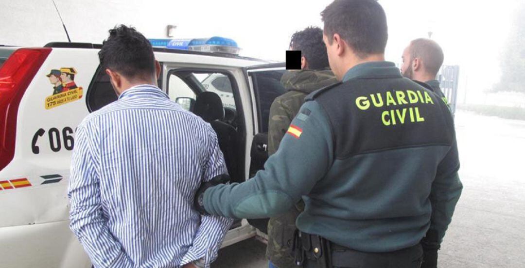 Los detenidos en Ibros son conducidos a un vehículo por agentes de la Guardia Civil.