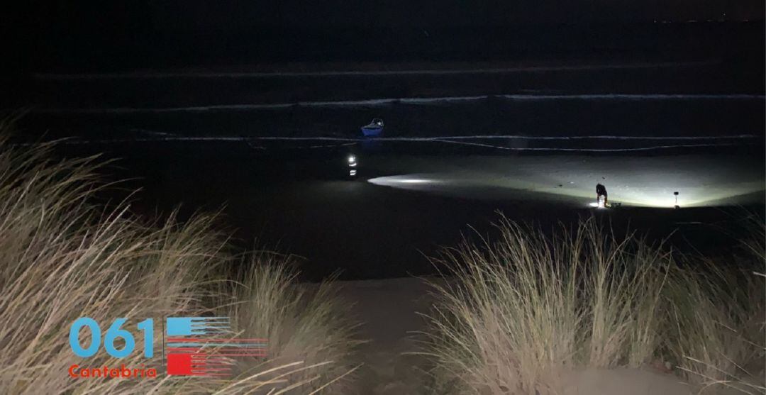 La pequeña embarcación en la que iban los dos pescadores continúa varada en la playa Salvé de Laredo, mientras los servicios de emergencias buscan al hombre desaparecido, arrastrado por la corriente.