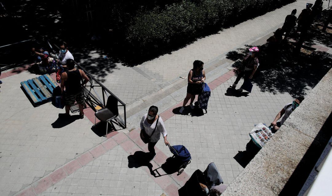 Colas de personas esperan a las puertas de la Parroquia Santa María Micaela de Madrid para recibir alimentos