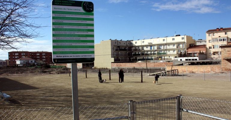 Primer espai caní de Mollerussa amb el cartell amb la normativa en primera instància i alguns propietaris amb els seus gossos al fons, el 18 de gener de 2016.