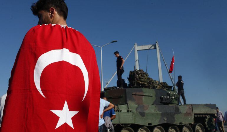 Varios manifestantes, junto a unos tanques en el puente sobre el Bósforo en Estambul.