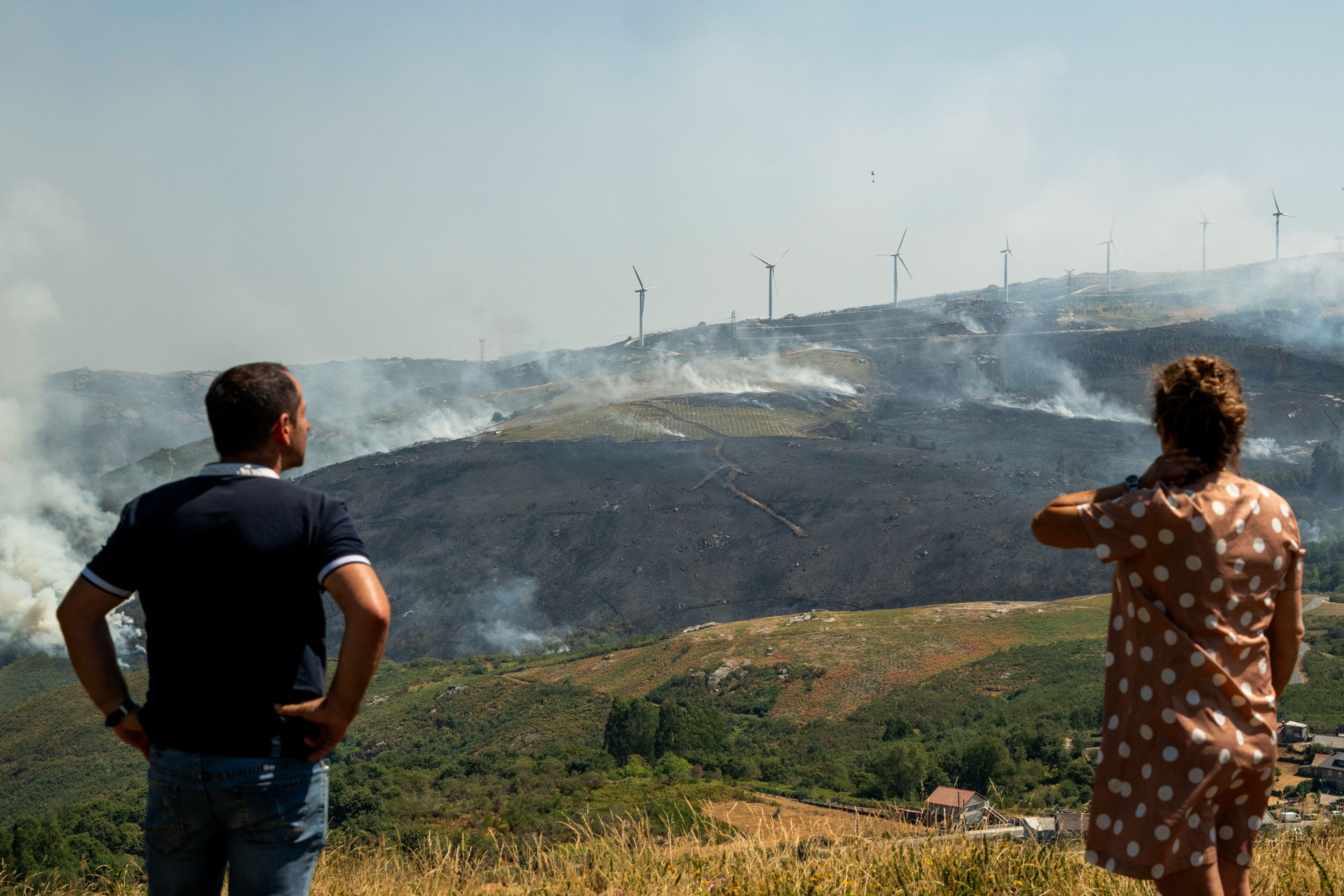 Varias personas observan el incendio forestal declarado en Avión (Ourense), este lunes