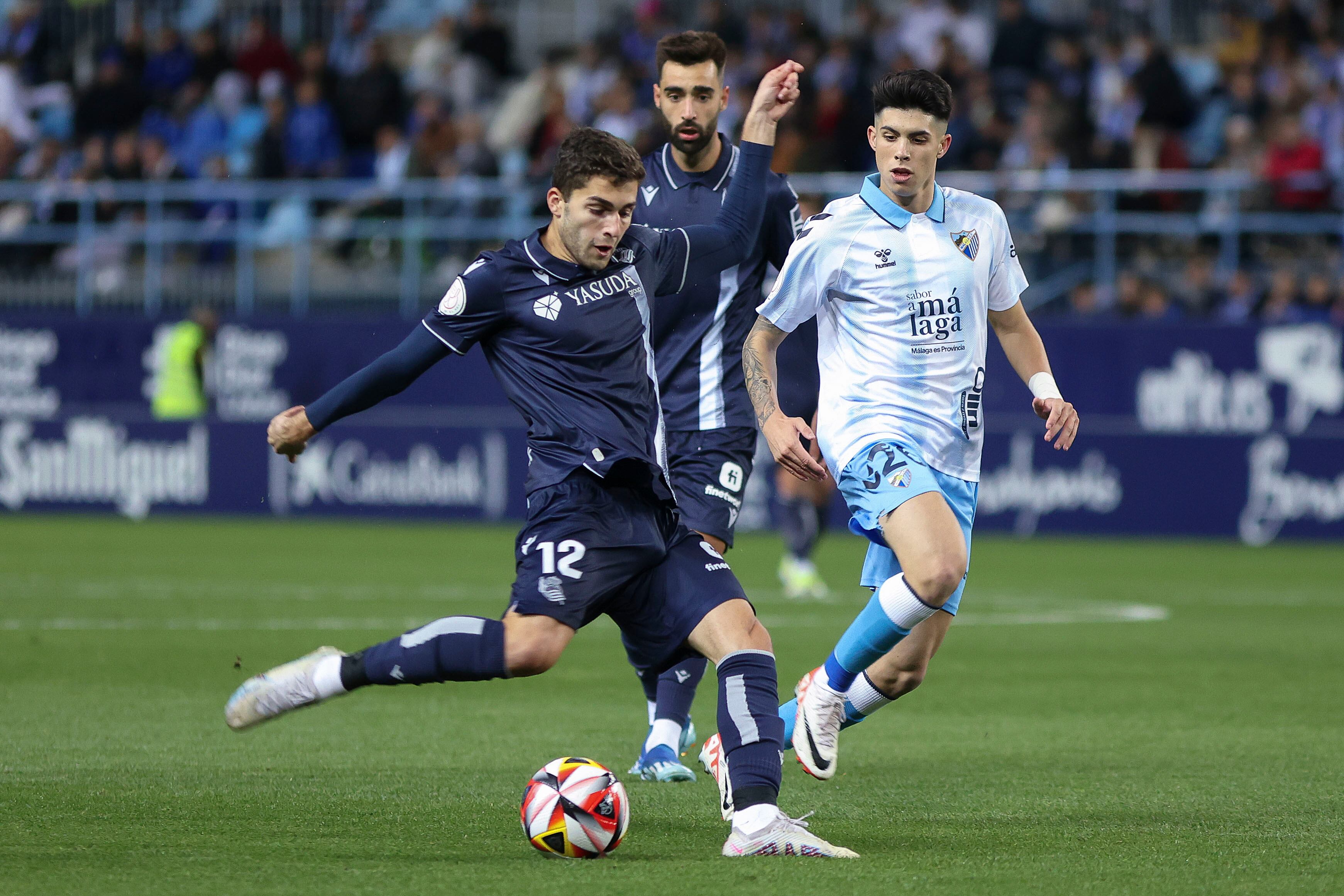 Málaga (España) 07/01/2024.- El delantero ruso de la Real Sociedad Arsen Zakharyan (i) dispara junto a Antonio Cordero (d), del Málaga CF, durante el partido que enfrenta hoy domingo al Málaga CF y a la Real Sociedad en el estadio de La Rosaleda en dieciseisavos de final de la Copa del Rey. EFE/Daniel Pérez
