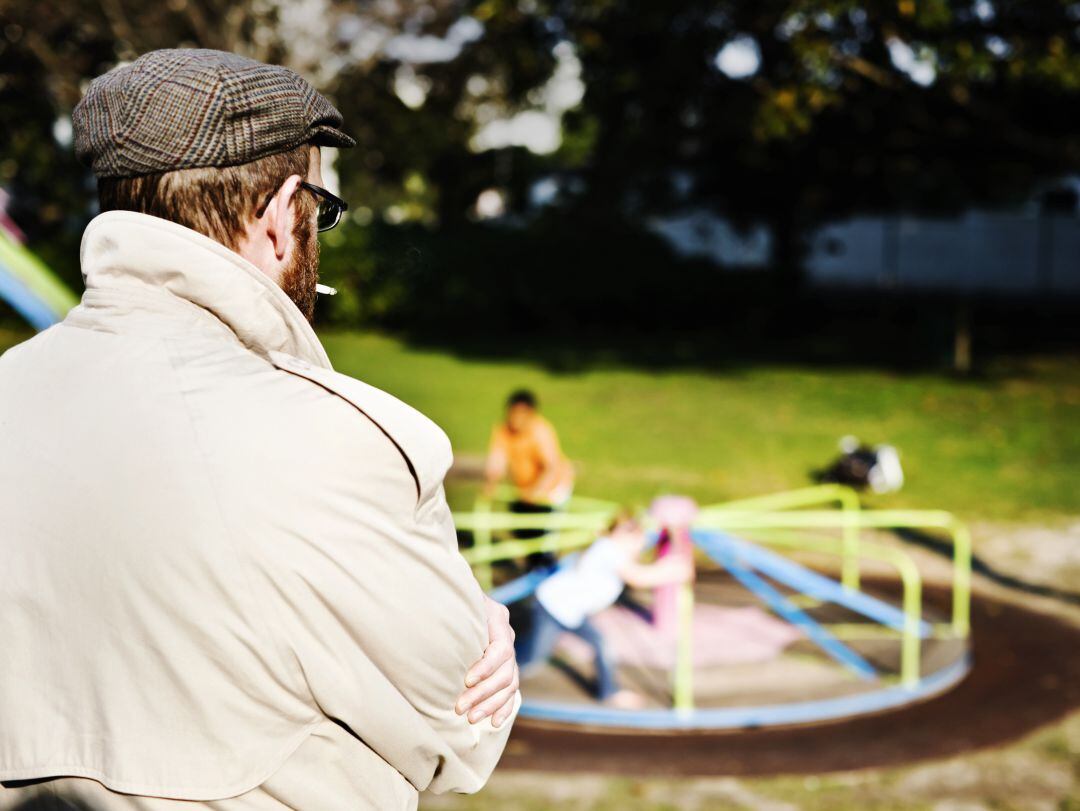 Un hombre observa a unos niños en el parque. 