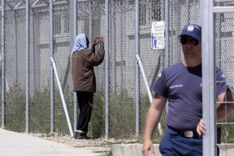 Un hombre mira a través de la valla del centro de detención de Moria, situado en la isla de Lesbos, Grecia