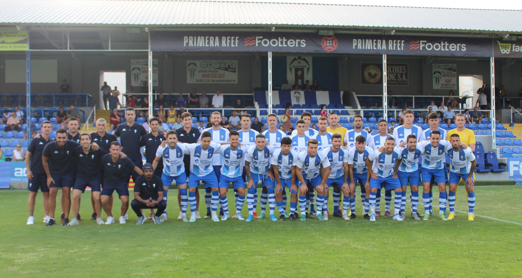 Plantilla y staff técnico 2022-23 posan ante la grada de Tribuna del campo del Collao