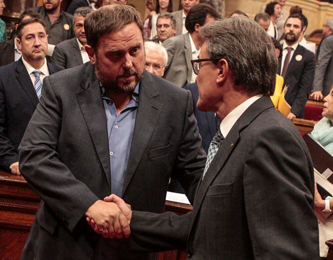 Artur Mas y Oriol Junqueras se saludan en el último pleno del Parlament, que aprobó la Ley catalana de Consultas