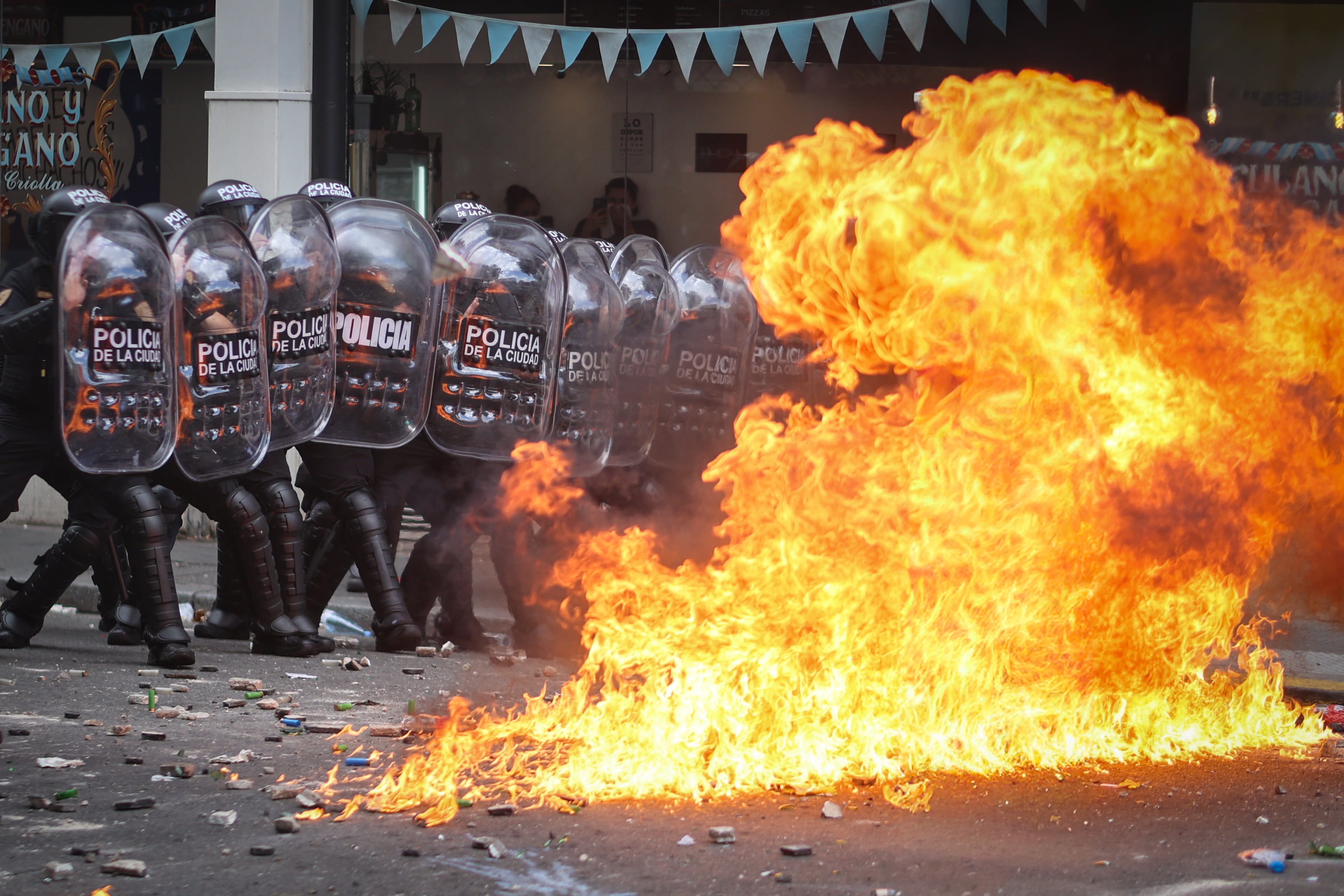 Integrantes de la Policía de Argentina se cubren durante un enfrentamiento con manifestantes en Buenos Aires (Argentina).