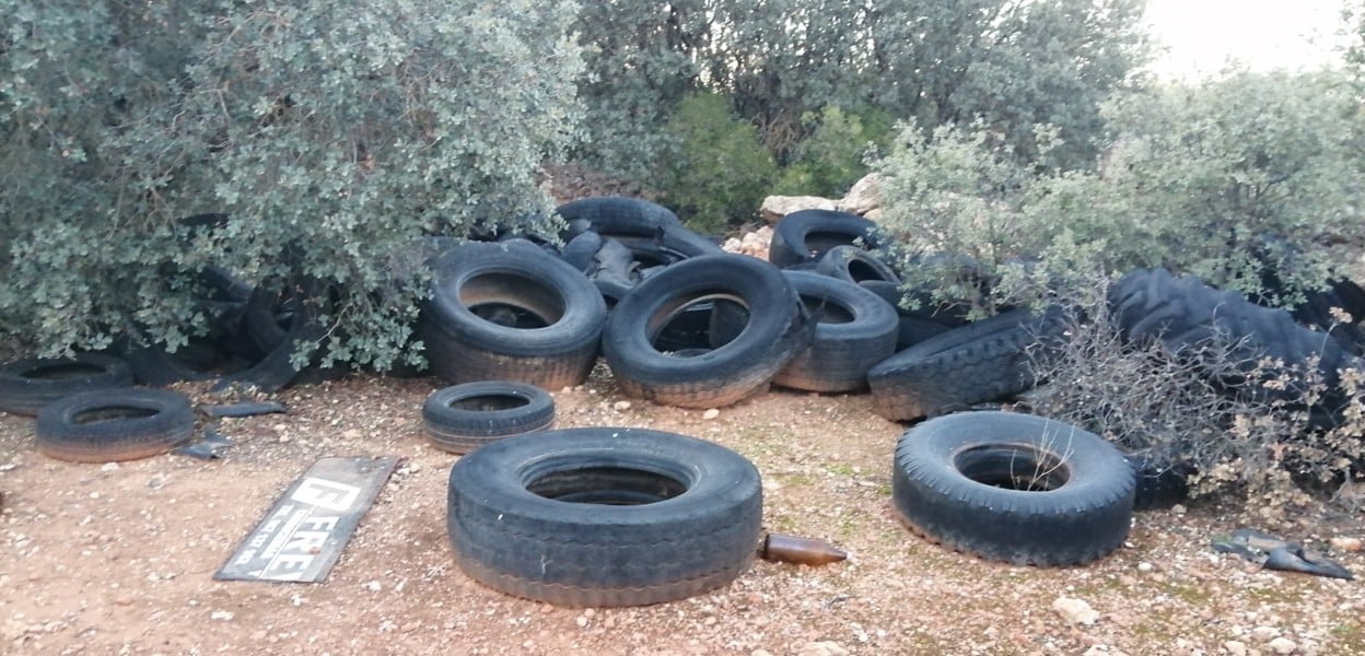 Imagen de los neumáticos metidos entre la maleza en uno de los espacios con basura de San Clemente