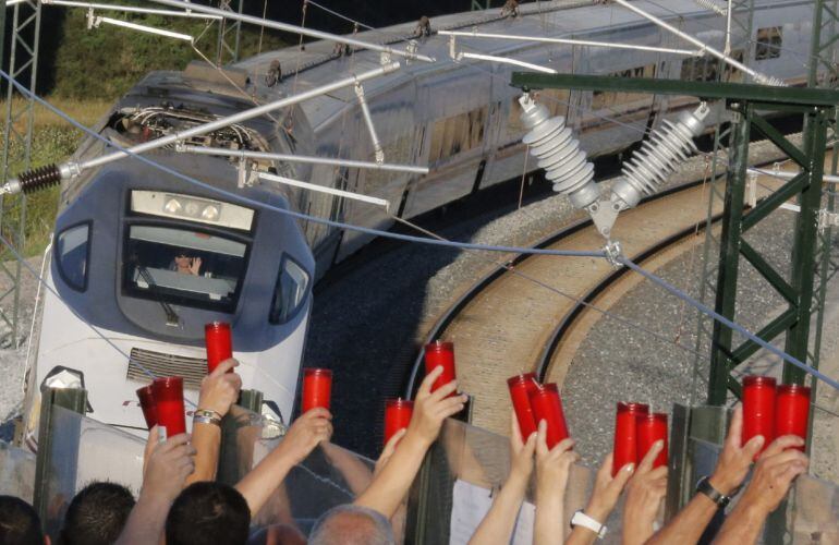 Tramo en el que descarriló el Alvia, a la altura de Angrois, donde varias personas portan velas al paso de un tren.