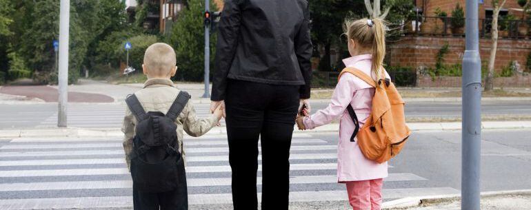 Dos niños, junto a su madre, camino del colegio