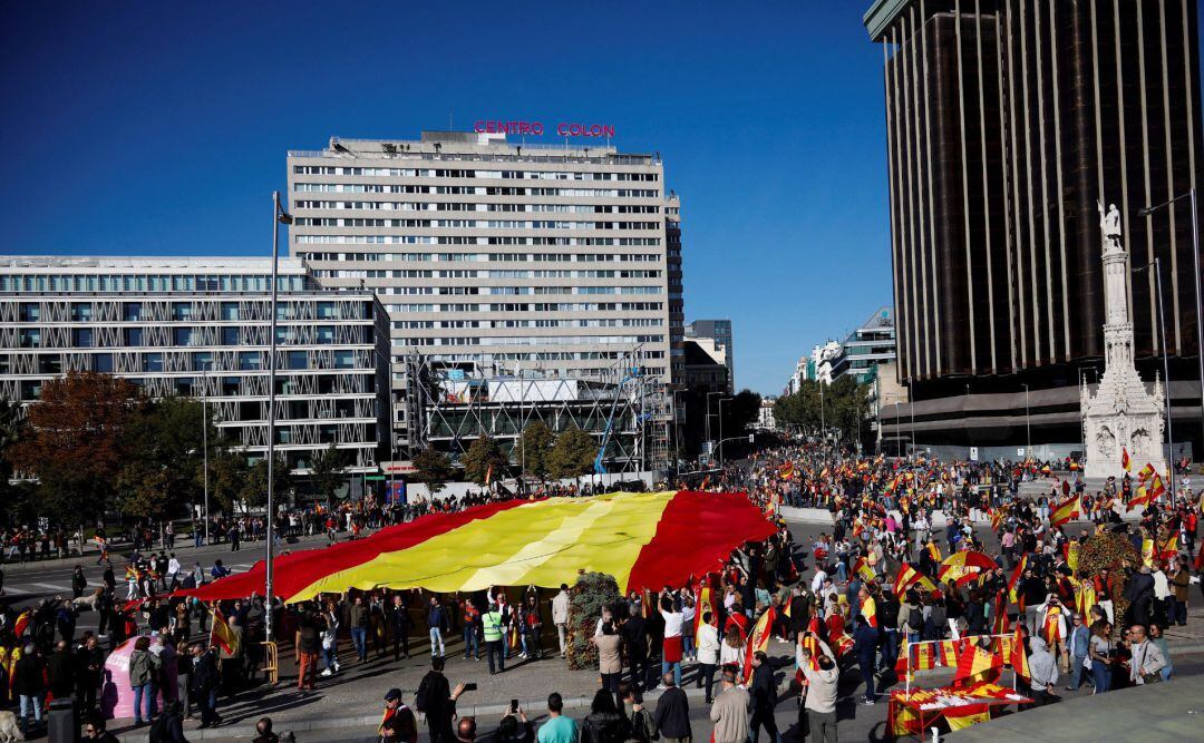 Decenas de personas sostienen la bandera de España de 1.000 metros cuadrados -50 de largo por 20 de ancho y con unos 130 kilos de peso, durante la concentración convocada por Vox para defender la &quot;unidad de España, el orden constitucional y la convivencia nacional&quot; este sábado en la madrileña Plaza de Colón. La enseña, que según la petición a la empresa fabricante es la más grande de la historia, ha sido portada desde la calle Génova -la calle donde se encuentra la sede del PP- hasta la plaza de Colón.