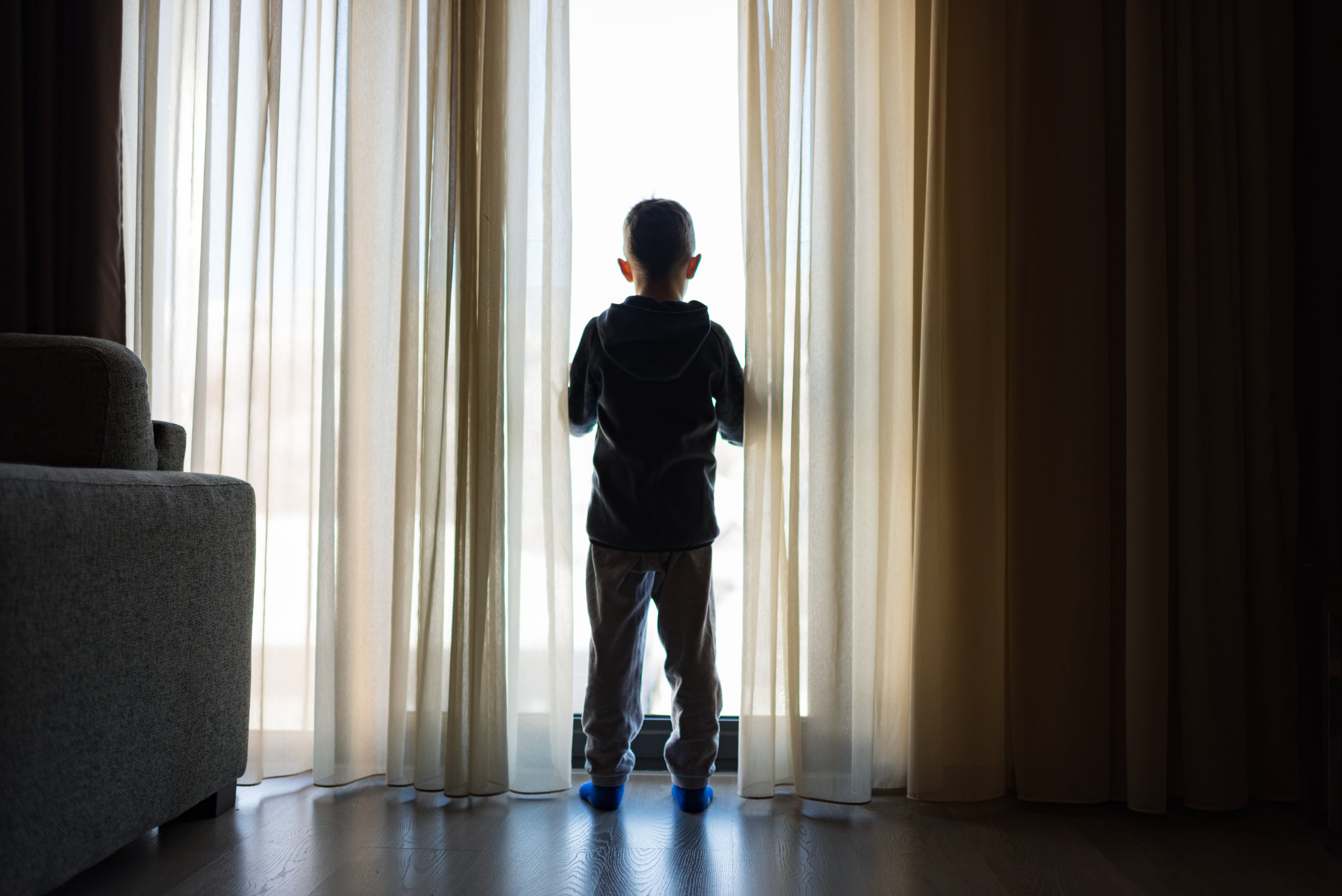 Foto de archivo de un niño de espaldas a una ventana.