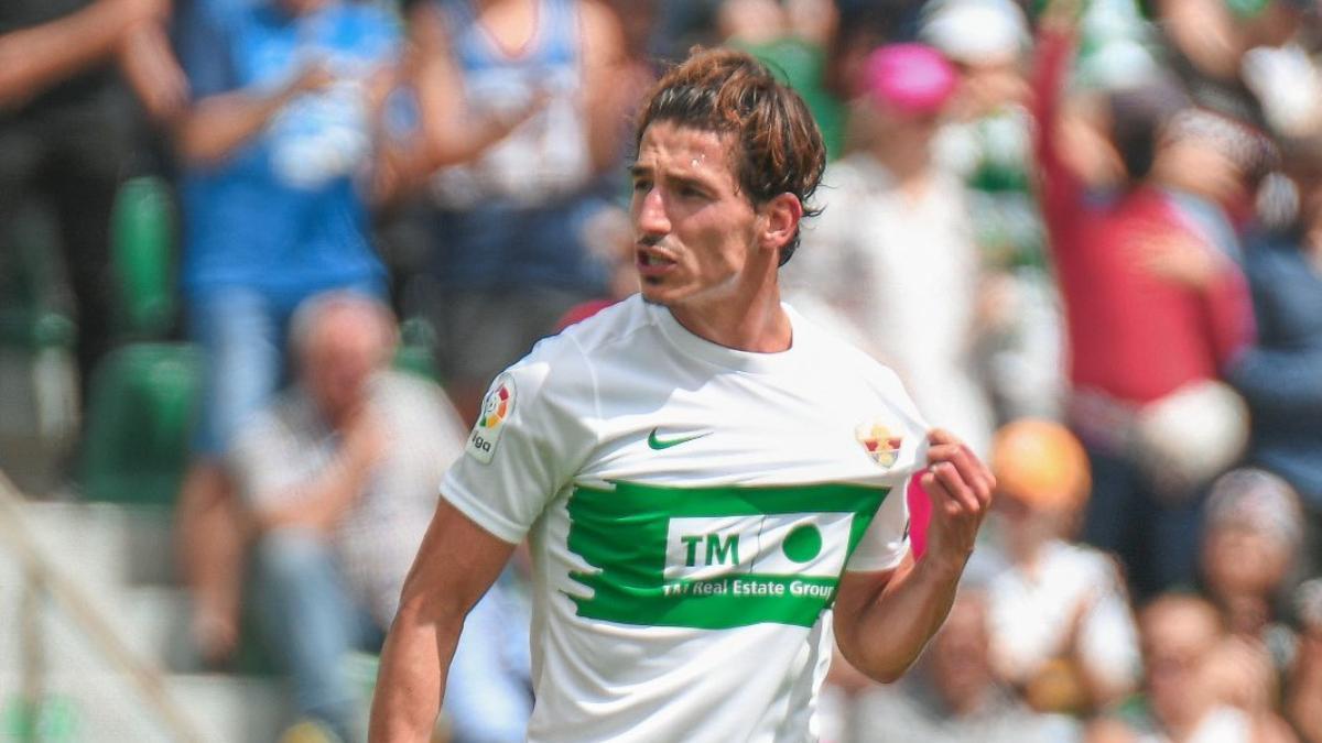 Pere Milla celebra un gol con el Elche mostrando el escudo