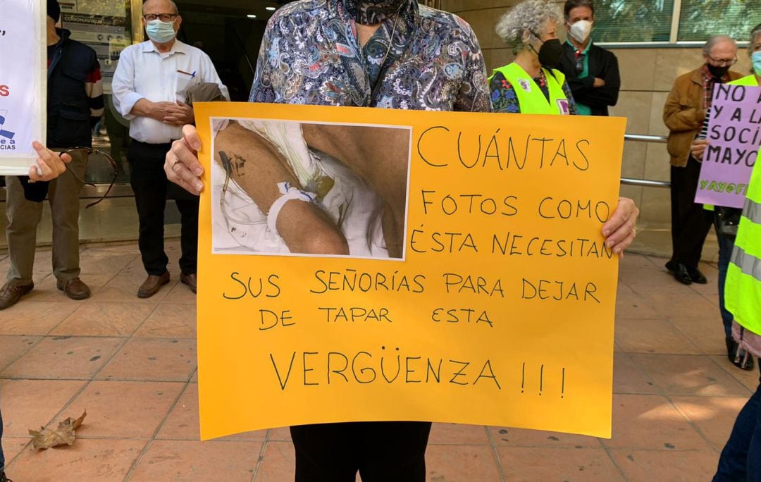 Familiar de un residente muestra una pancarta con una foto donde queda claro la precariedad con la que trabajan las TECAE por falta de medios y personal, mostrando su malestar porque la Asamblea Regional no haya querido investigar lo que ocurre