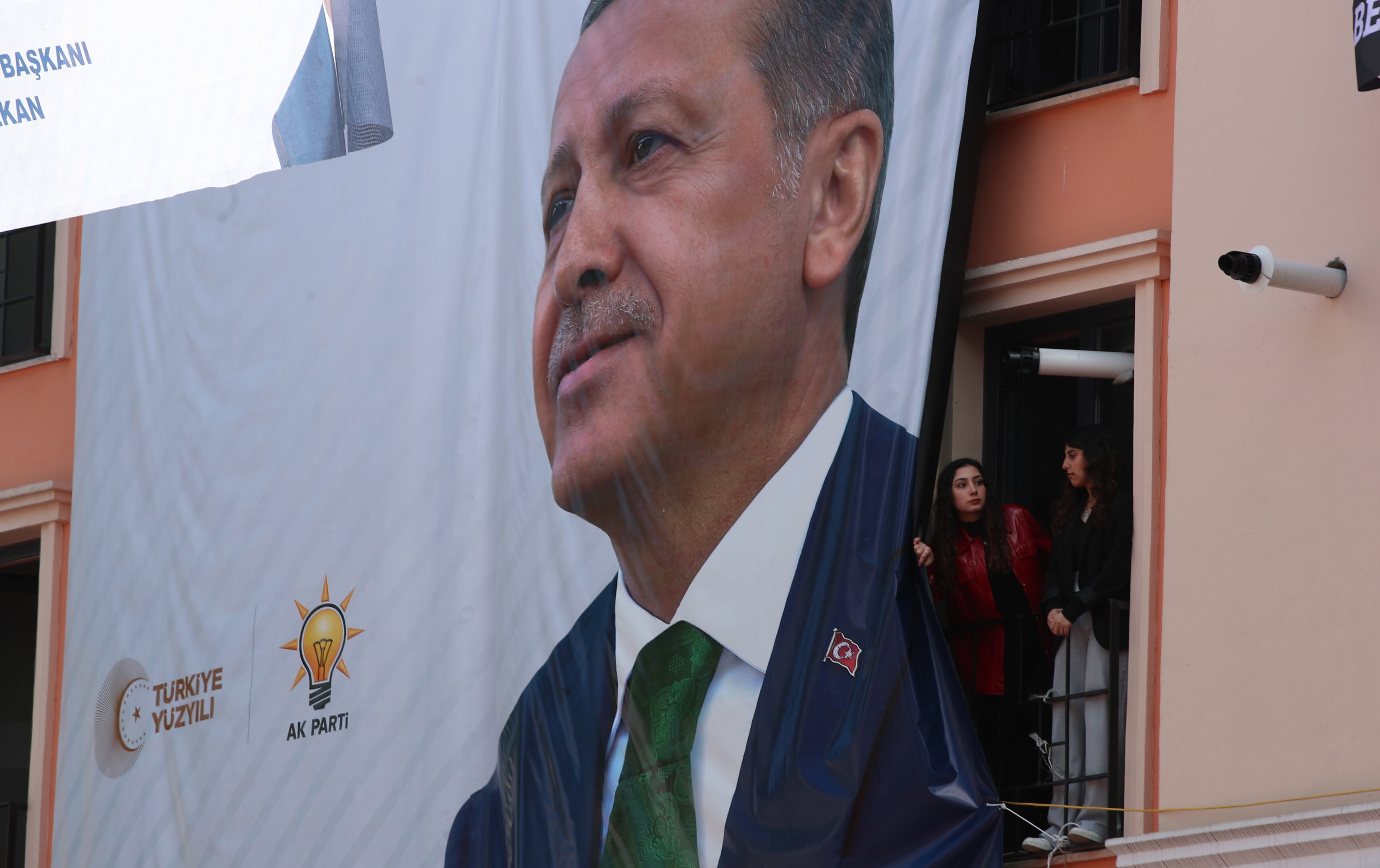 Una mujer retira parcialmente un cartel electoral de Erdogan en Estambul