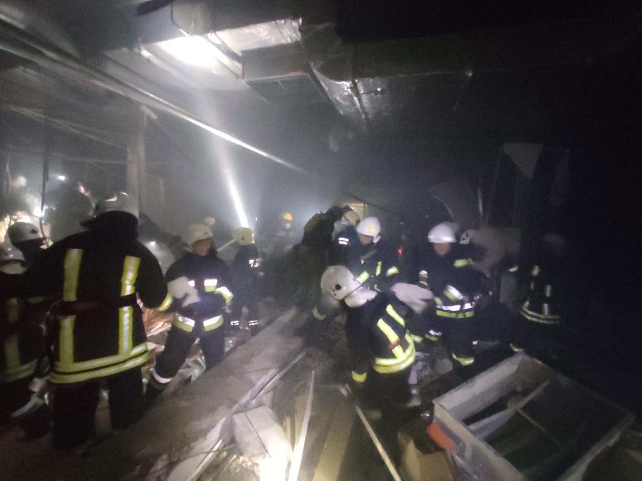 Los servicios de emergencia trabajan en la búsqueda de víctimas en el centro comercial de las afueras de Kiev alcanzado por los bombardeos rusos.