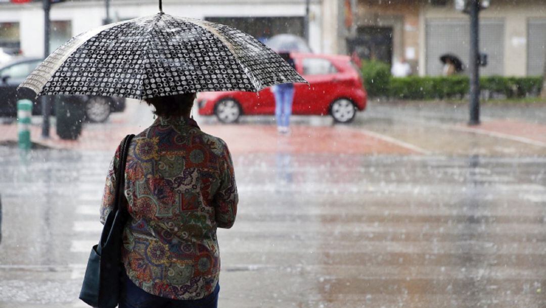 Una mujer se protege bajo la lluvia en una foto de archiva en València