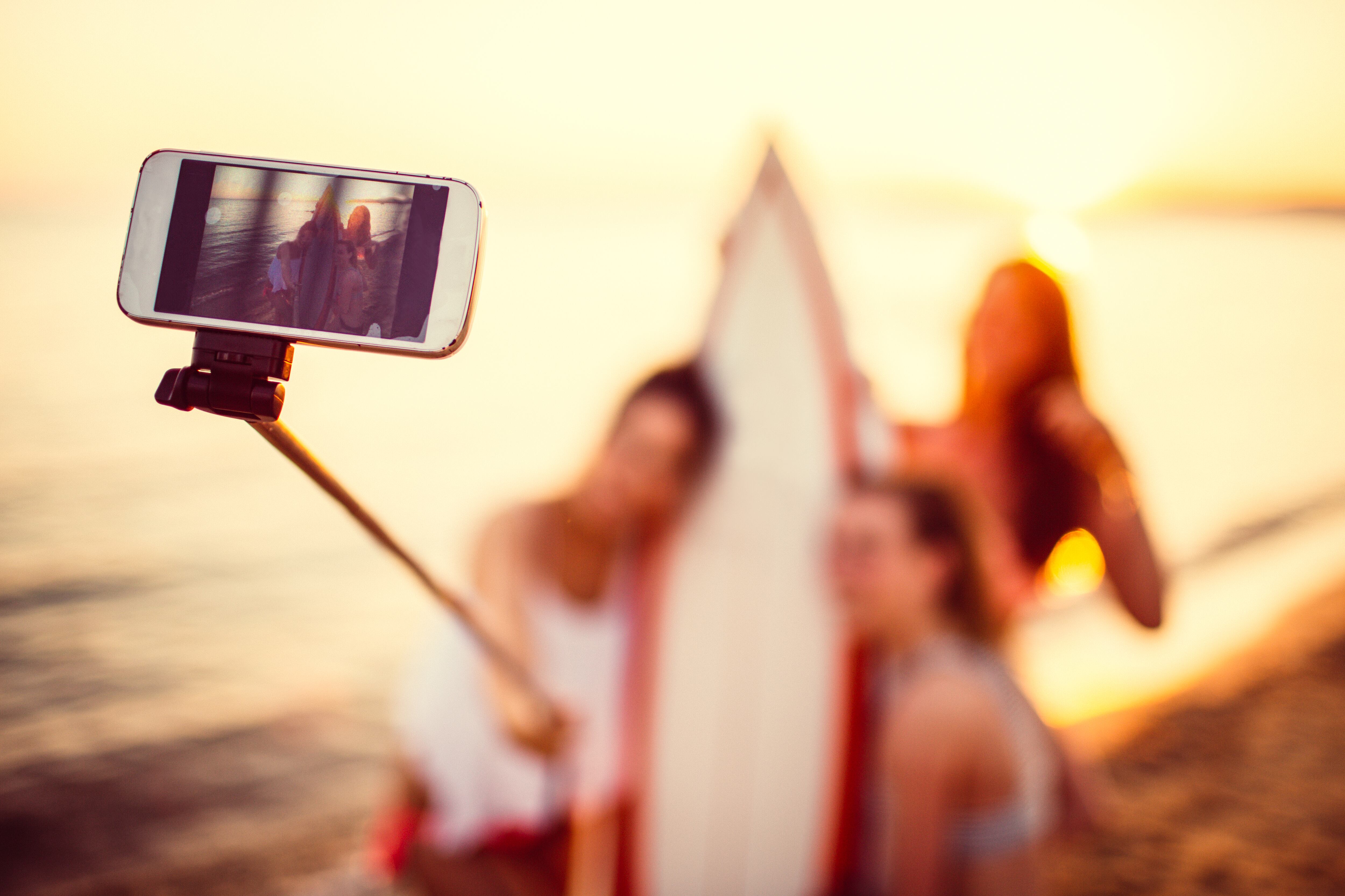 Photo of a smiling surfer girls making selfie at the beach