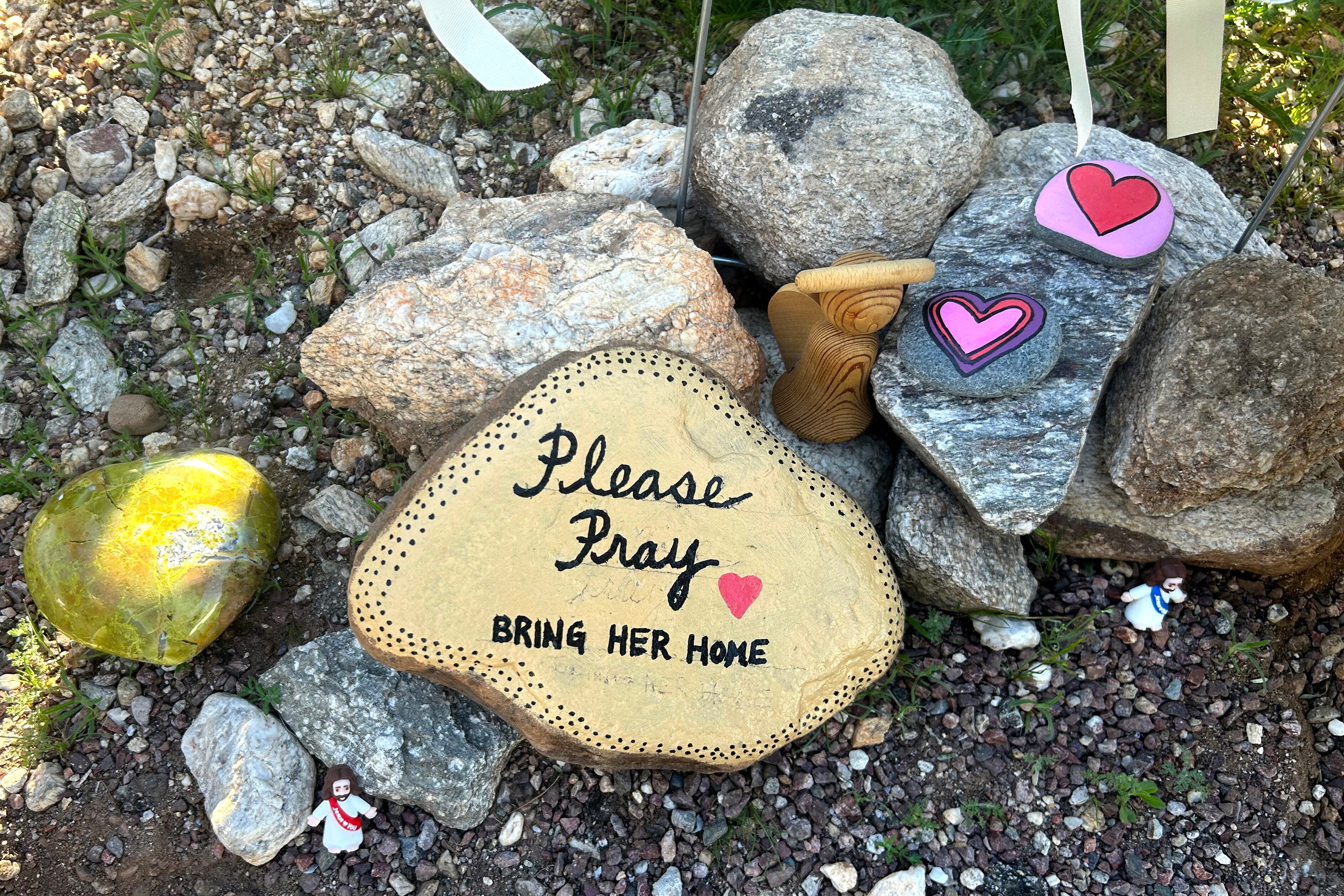 Fotografía de un altar donde aparece una piedra pintada de amarillo que dice "Por favor, oren. Tráiganla a casa" frente a la casa de Nancy Guthrie este miércoles, en Catalina Foothills (Az, EE.UU.).