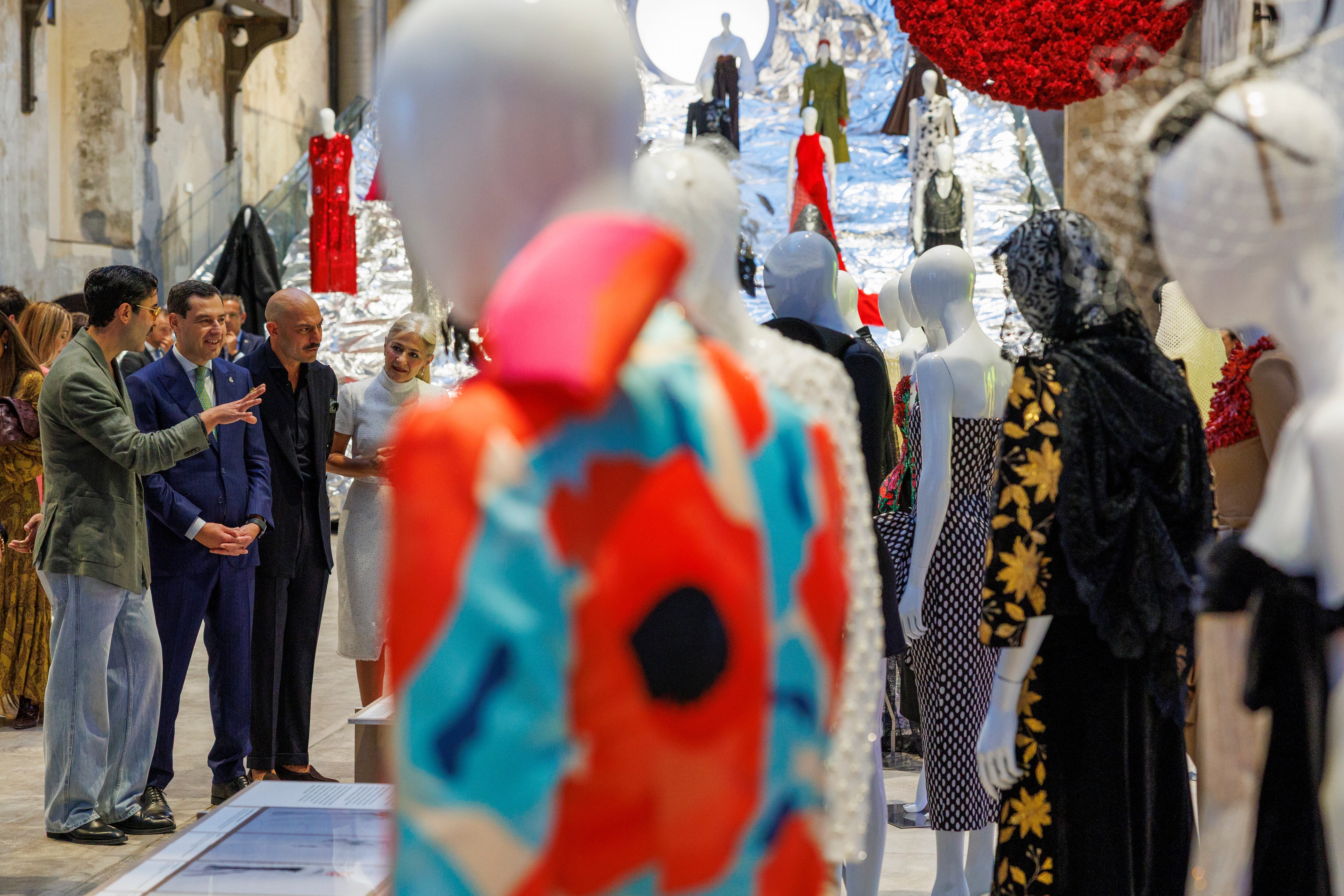 SEVILLA, 28/10/2025,- El presidente de la Junta de Andalucía, Juanma Moreno (2i), junto al comisario de la muestra, Raúl Romero (3i) y a la consejera de Cultura, Patricia del Pozo, este martes en la inauguración de la exposición ?Lux: la moda andaluza en la cultura del siglo XXI? que tiene lugar en la Fábrica de Artillería de Sevilla. EFE/ Julio Muñoz