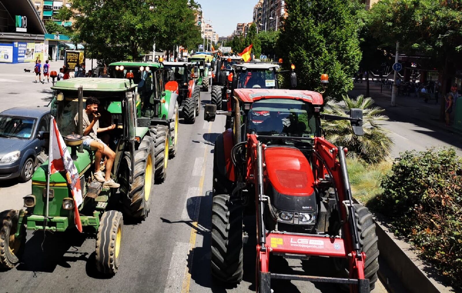 Una tractorada recorre una ciudad española durante una mañana soleada.