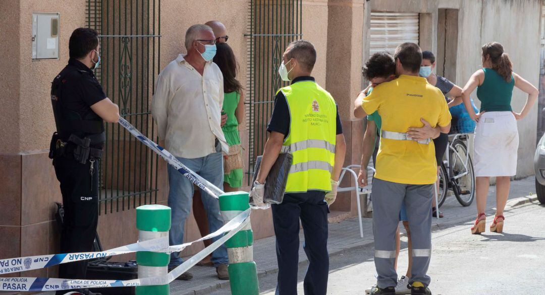 El marido y el hijo de la mujer de 47 años hallada muerta se abrazan esta tarde en el exterior del número siete de la calle Arizona de la pedanía murciana de Churra