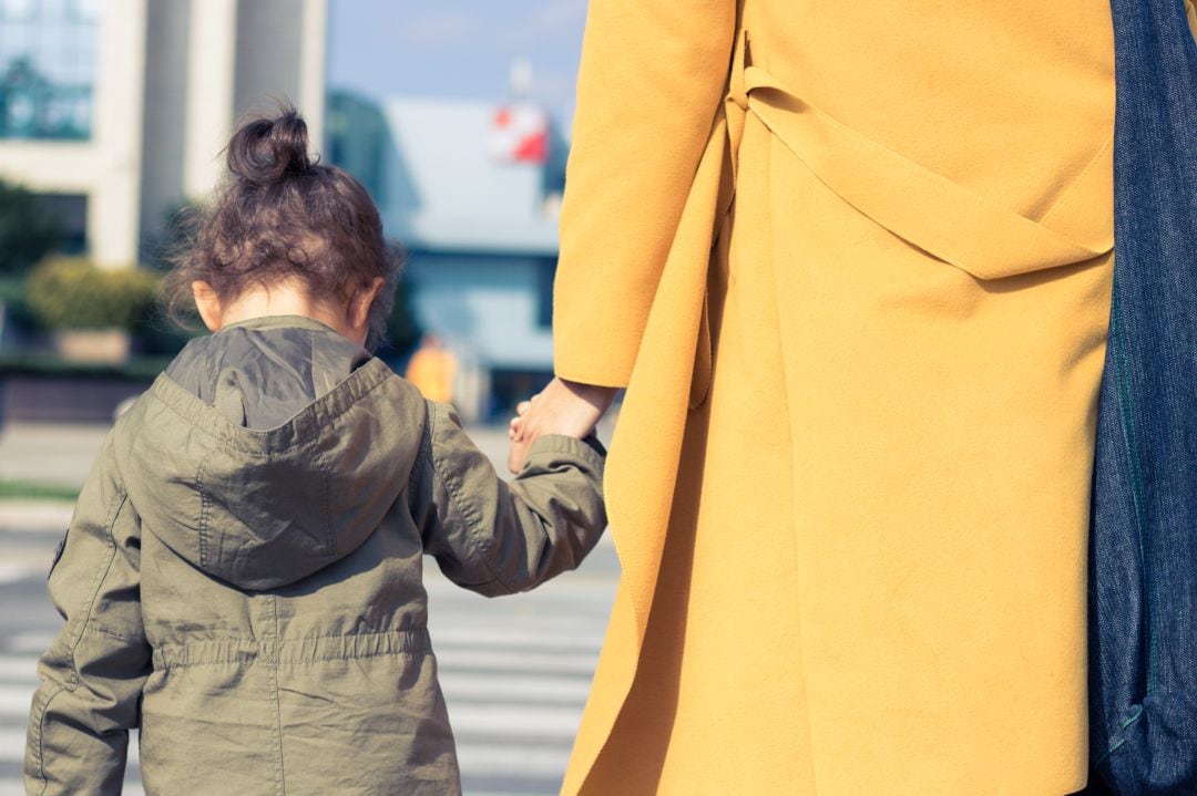 Niña sale a la calle acompañada por su madre