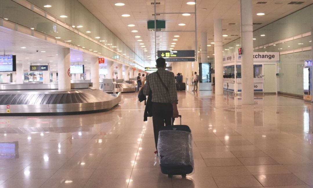 Un viatger caminant amb maletes a la zona d'arribades de la T1 a l'aerport del Prat el 19 de juny del 2020