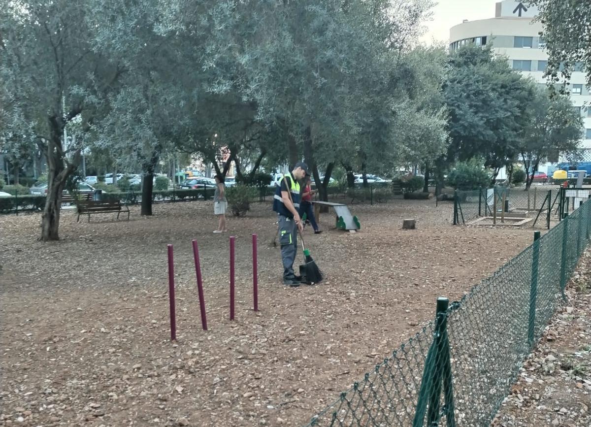 Un operario limpia el parque canino de Oliva.