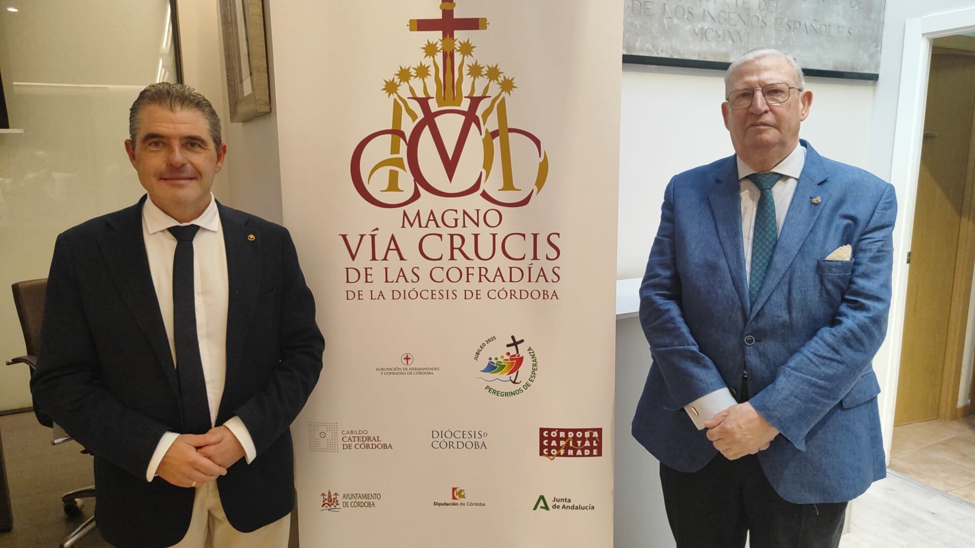 Los presidentes de los Consejos de Cofradías de Córdoba, izquierda, y Sevilla posan junto al logotipo del Magno Vía Crucis