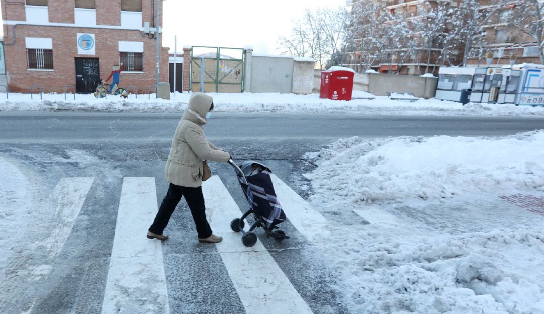 Una mujer camina con un carro de la compra por una vía nevada de Teruel.